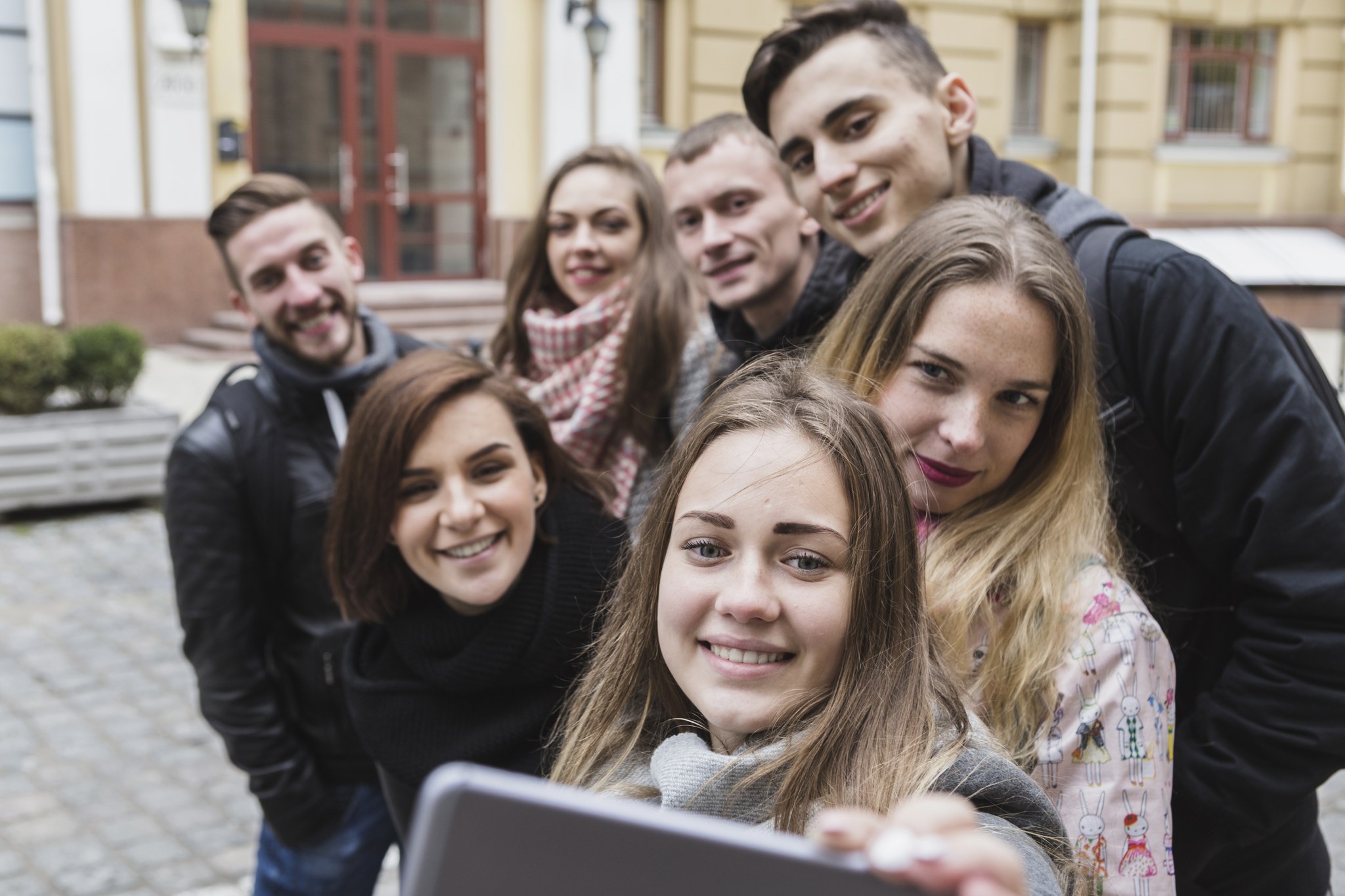 Ryhmä nuoria ottaa selfietä kännykällä.