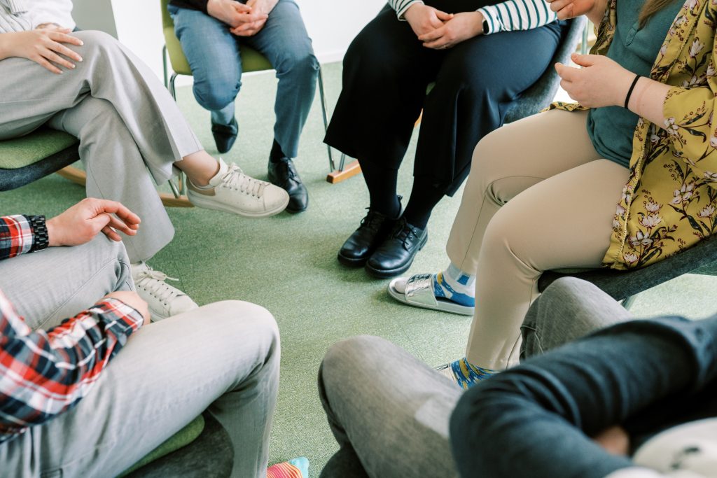 Kuva ihmisten jaloissa, kun ihmiset istuvat ympyrässä.