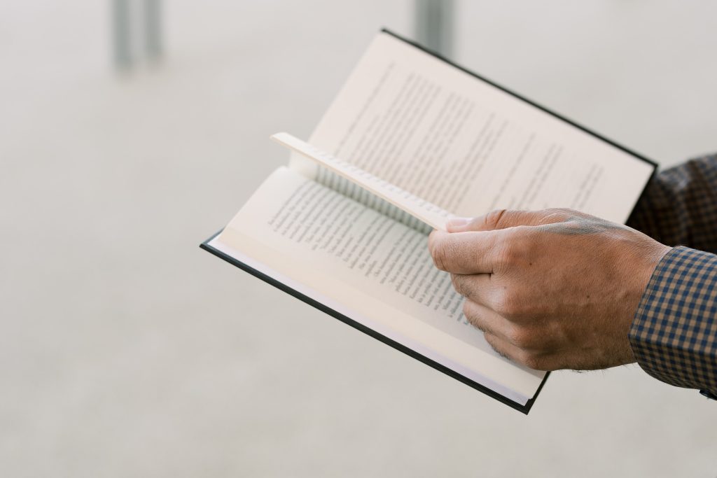 Kädet jotka pitelevät kirjaa.