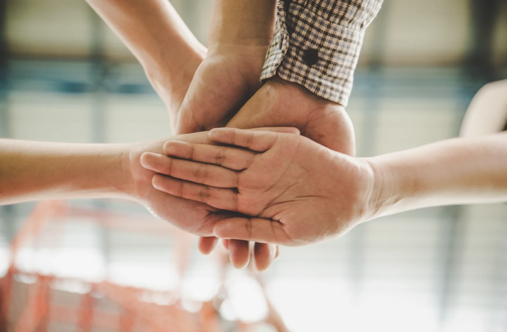 Joukko ihmisten kämmeniä toistensa päällä yhteistyön merkkinä.
