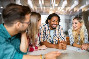 Ryhmäkeskustelutilanne, nauravia ihmisiä pöydän äärellä.